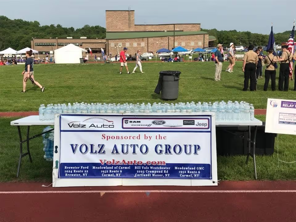 Table with water bottles and a Volz Auto Group sponsor banner.