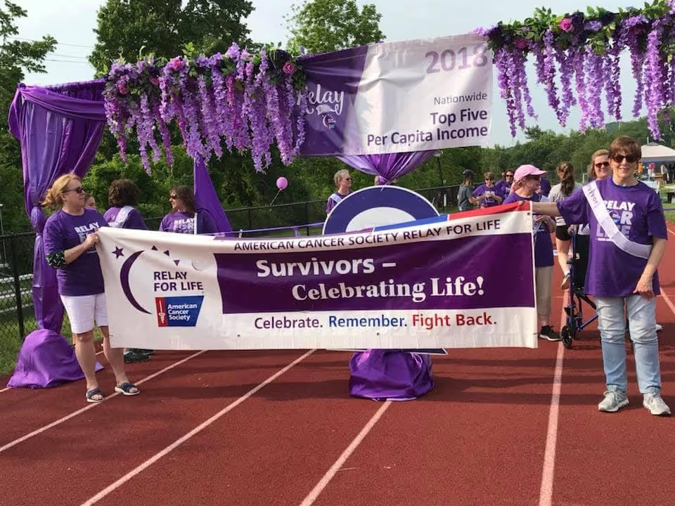 Participants holding a Relay For Life “Survivors – Celebrating Life” banner.