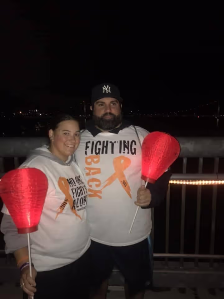 Two people holding red lanterns at a night event.