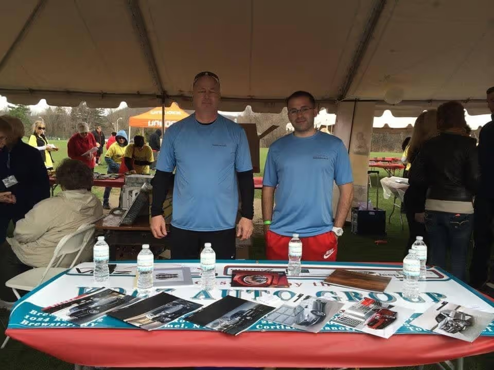 Two men standing behind a display table at an outdoor event.