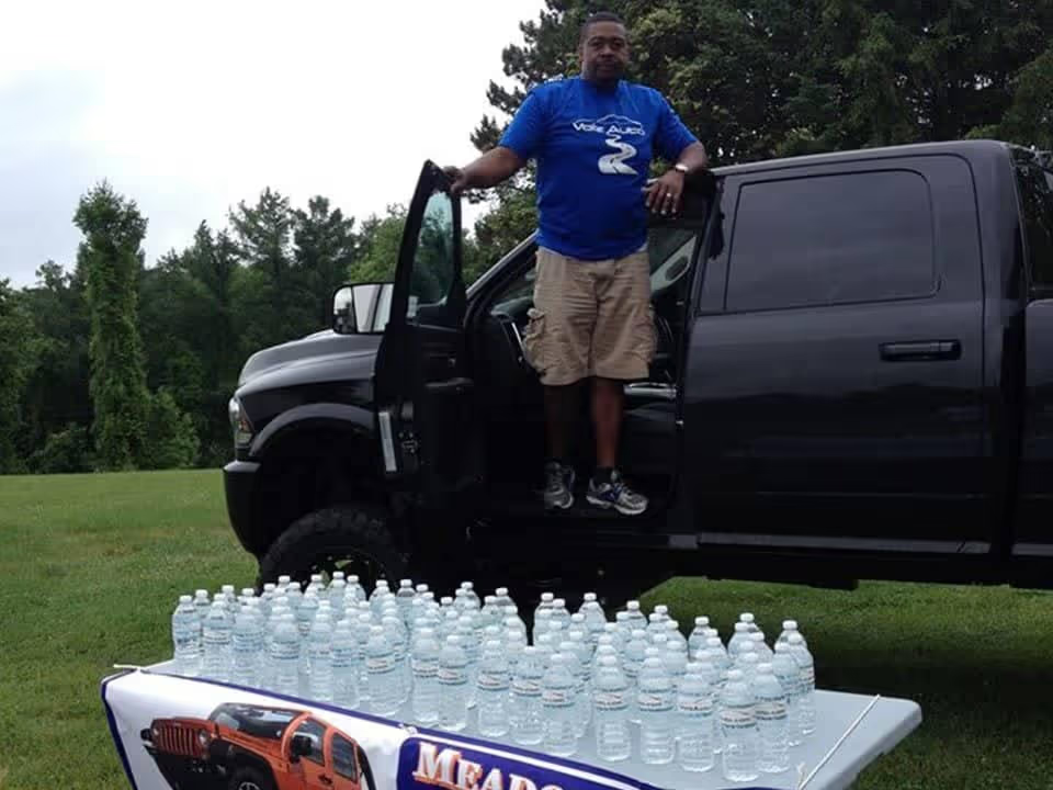 Man standing by a truck with a table of water bottles.