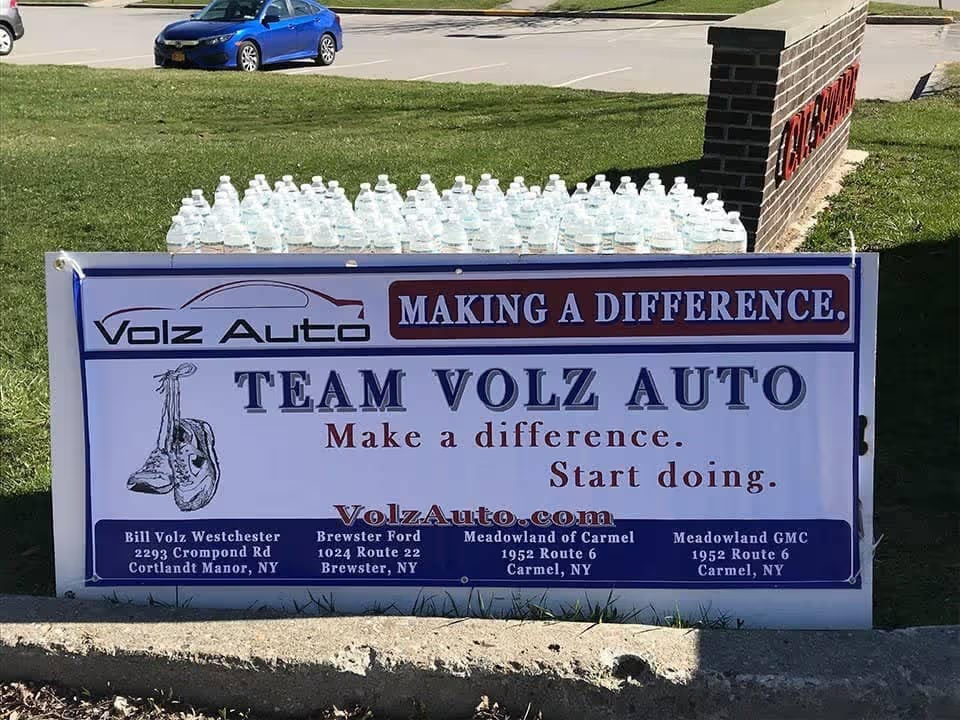 Team Volz Auto banner displayed with water bottles on the grass.