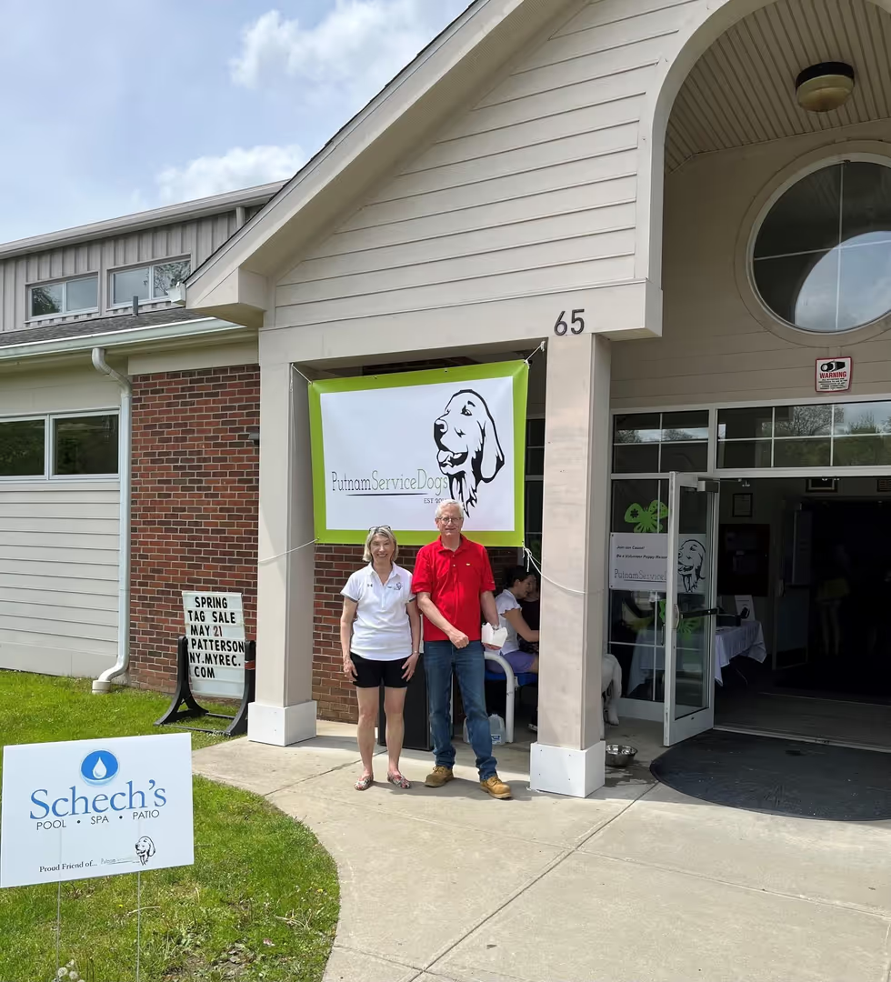 Two people standing outside a building with a Putnam Service Dogs banner.