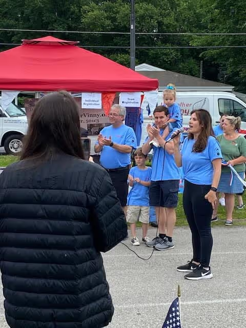 Group in blue shirts speaking at an outdoor event.