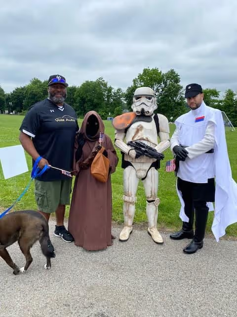 Four people posing, including two in Star Wars costumes, with a dog.#